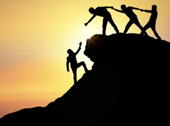 Team of students helping each other climb a rocky peak at sunset, symbolizing collaborative problem-solving and design thinking in STEM lessons
