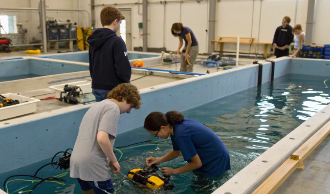 Students testing underwater robots in a large indoor water tank, showing the WaterBotics underwater robotics program reshaping student confidence in action
