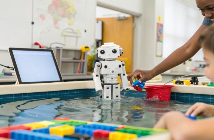Students using a tablet, building blocks and a robot in a water tray, showing how games and interactive technology support hands-on STEM learning
